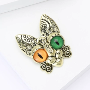 Detailed macro of vintage gold animal brooch with green and orange resin eyes