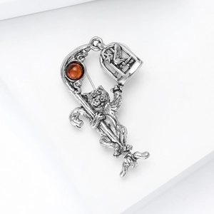Macro detail of vintage silver cat brooch with amber gemstone and birdcage pendant