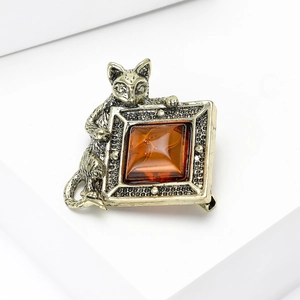 Vue macro d'une broche chat vintage avec une pierre carrée en résine ambrée incrustée