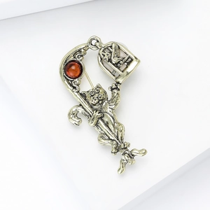 Detail of vintage cat brooch with red gemstone and birdcage pendant in antique silver