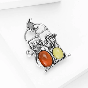 Detail of vintage silver cat brooch with amber red and yellow gemstones on white steps