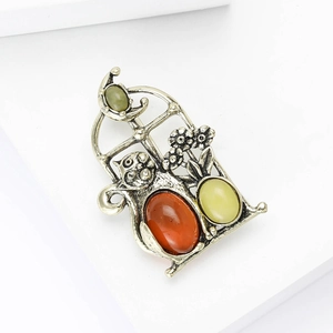 Detailed view of vintage alloy cat brooch with amber gemstone and floral window frame