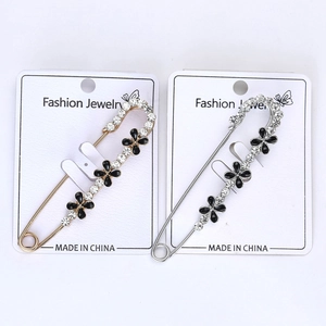 Détail de broches trèfle à quatre feuilles or et argent avec huile noire et cristaux