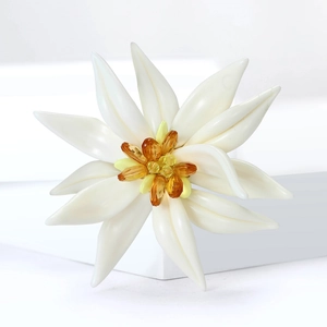 Détail d'une broche edelweiss en émail blanc avec pierres précieuses jaunes au centre
