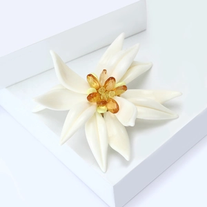 Élégante broche fleur d'edelweiss en émail avec centre en perles d'ambre sur socle blanc