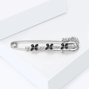 Détail d'une broche argentée avec fleurs en émail noir et strass étincelants
