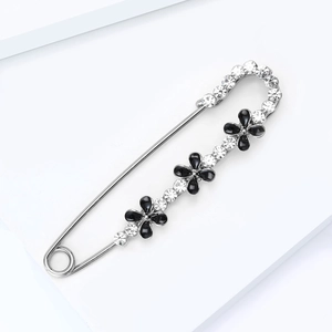Détail d'une broche épingle argentée avec strass brillants et fleurs en émail noir