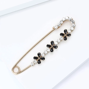 Vue détaillée de la broche épingle dorée avec fleurs noires et strass étincelants