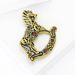 Vintage gold-plated rocking horse brooch with enamel flower accents on white geometric stand