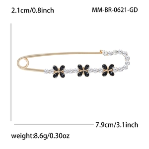 Broche épingle dorée avec trèfles noirs et strass scintillants sur fond blanc