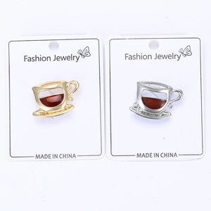 Détail des broches tasses à café en or et argent avec émail sur carte de présentation
