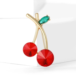 Exquise broche cerise dorée avec cristaux rouges facettés et feuille verte sur fond blanc