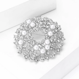 Detailed close-up of a silver wreath brooch with sparkling crystals and white pearls