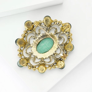 Vue arrière d'une broche baroque avec strass verts et finition métal doré vieilli