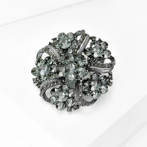 Vintage gunmetal floral wreath brooch with smoky crystal rhinestones on a white pedestal