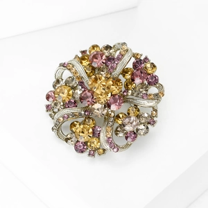 Macro shot of colorful rhinestone floral brooch with silver alloy base on white background