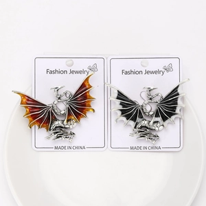 Exquisite dragon brooches in red and black enamel wings on a ceramic display plate