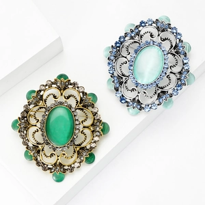 Broches baroques vintage avec cristaux et pierres émeraude sur des blocs de marbre