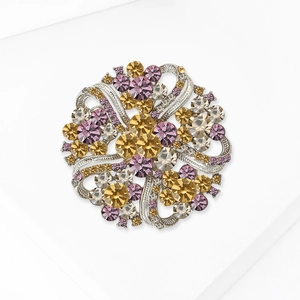 Detailed view of silver crystal wreath brooch with purple and yellow rhinestones
