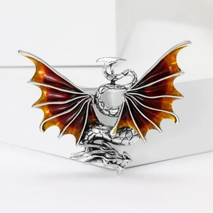 Macro detail of dragon brooch showing red enamel wings and silver metallic scale textures