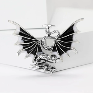 Detailed close-up of a silver dragon brooch with black and white enamel wings and scales