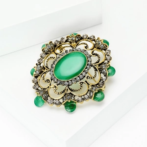 Détail de la broche baroque vintage avec œil de chat vert et strass gris brillants