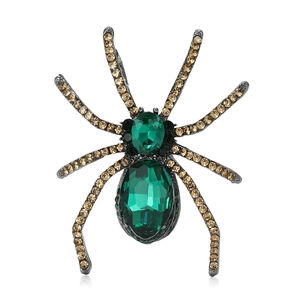 Vintage spider brooch with green faceted gems and champagne rhinestones on white background