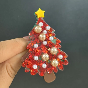 Close-up of red acrylic Christmas tree brooch with pearls and glitter surface