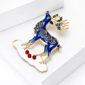 Broche cerf de Noël exquise en émail bleu roi avec détails dorés sur un support blanc