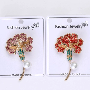 Detail of carnation brooches featuring pink and red rhinestones with pearl accents