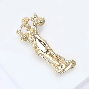Detailed macro view of a golden Lady Justice alloy brooch with scales on a white podium