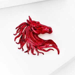 Macro view of bright red glossy horse head metal brooch with streamlined mane detail