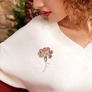 Detail of carnation brooch with gradient rhinestones and white pearl on white sweater