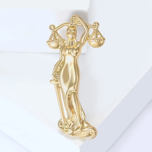 Macro shot of mirror-polished gold Lady Justice brooch with scales and sword details