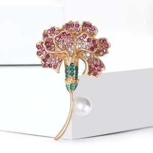 Elegant gold flower brooch with red rhinestones and white pearl on a white pedestal