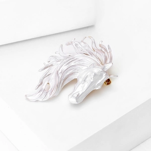 Detail of horse head brooch with white and pink enamel finish on gold metal base