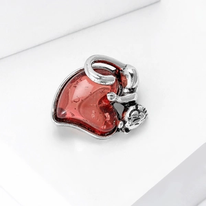 Detailed macro view of a vintage silver monkey embracing a red sparkling heart pendant