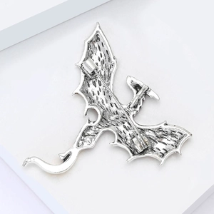 Detailed macro view of the silver dragon brooch with vintage texture and safety pin clasp