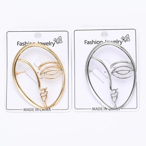 Detailed view of minimalist gold and silver wire face profile brooches on cards