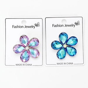 Gros plan de broches fleurs en cristal étincelant bleu et violet sur cartes bijoux