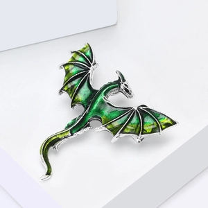 Macro shot of green enamel dragon brooch showing detailed metal texture and vibrant gradient wings