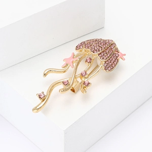 Detail of golden jellyfish brooch featuring pink crystals and starfish on white blocks