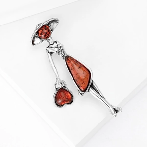 Vintage silver lady brooch with hat and amber resin inserts on a white background