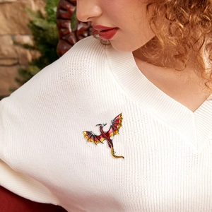 Detailed view of red enamel dragon brooch worn on a stylish coat in a festive setting