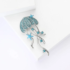 Macro detail of jellyfish brooch with blue crystals and silver tentacles on white base