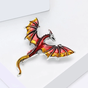 Detail of western dragon brooch with red-yellow enamel and silver wings on white stand
