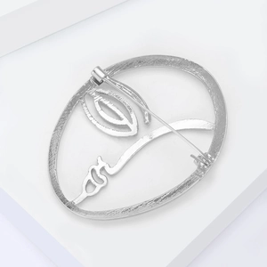 Close-up of silver minimalist abstract face brooch with linear artistic profile detail