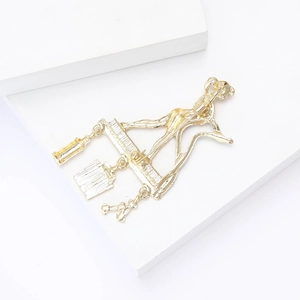 Exquisite gold alloy brooch featuring a modern character with hanging charms on white stone