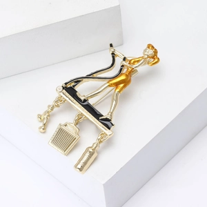 Elegant gold-tone female figure brooch with black enamel and three hanging charms