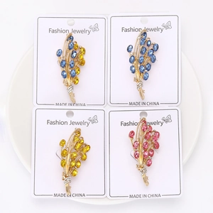 Dettaglio delle spille a spiga di grano in cristallo blu, giallo e rosa su base oro